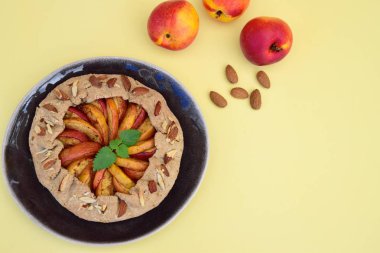 Şeftalili ve nane yaprağıyla süslenmiş badem fıstıklı bir galette. Düz yatıyordu