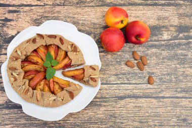 Şeftalili ve nane yaprağıyla süslenmiş badem fıstıklı bir galette. Düz yatıyordu