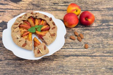 Şeftalili ve nane yaprağıyla süslenmiş badem fıstıklı bir galette. Düz yatıyordu