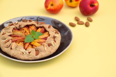 Şeftalili ve nane yaprağıyla süslenmiş badem fıstıklı bir galette. Düz yatıyordu