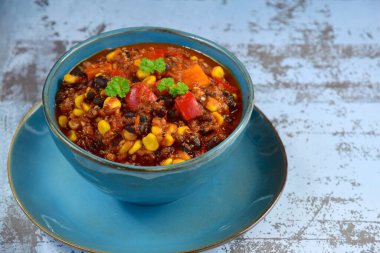 Black bean, quinoa, sweet potato, bell pepper and corn chili in a bowl garnish with parsley clipart