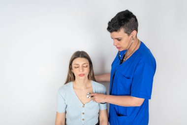 Endişeli genç bir hastayı muayene eden bir kadın doktor.