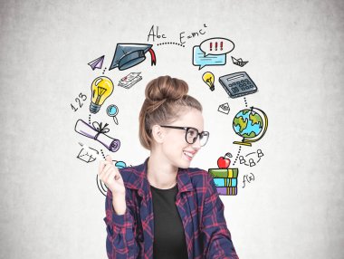 Gülümseyen bir kareli gömlek, siyah t gömlek ve bir kalem tutan ve yana doğru seyir gözlük takıyor kendine güvenen genç hipster kadın. Beton duvar ile bir renkli eğitim kroki