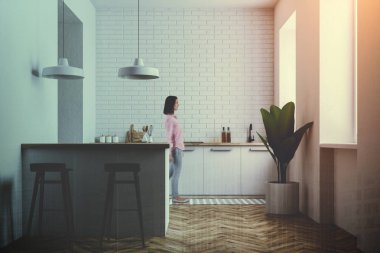 Gri ve beyaz duvar mutfak iç beyaz mutfak tezgahı, tabureleri olan çubuk ve duvarın yanında saksılı bir bitki ile yürüyen kadın. 3D render sahte kadar çift tonlu görüntü pozlaması