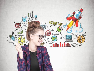 Gülümseyen bir kareli gömlek, siyah t gömlek ve bir kalem tutan ve yana doğru seyir gözlük takıyor kendine güvenen genç hipster kadın. Beton duvar ile kroki kadar bir başlangıç. Proje başlatma kavramı