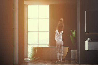 O bir modern banyo iç siyah duvarlı ayakta asılı bir yeşil havlu ile beyaz küvet. Sağdaki bir lavabo. Bir kadın. 3D render sahte kadar çift tonlu görüntü pozlaması