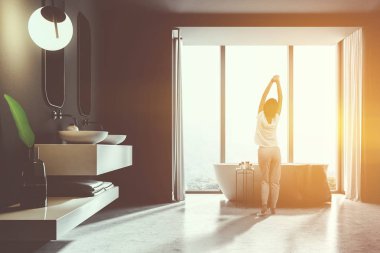 Kadın siyah taş duvarlar, beyaz mutfak tezgahı üzerinde bir çift lavabo duran ve üzerinde asılı bir iki dikey ayna banyo iç. Bir mermer zemin ve bir küvet. 3D render tonlu görüntü