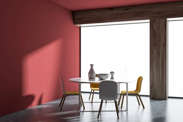 Red wall minimalistic Scandinavian style dining room interior with a concrete floor, a round table and four yellow chairs. A mock up wall and a panoramic window. 3d rendering