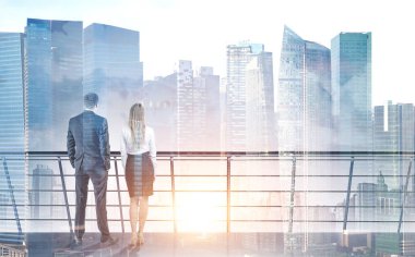 Bir balkonda duran ve güneş içinde modern bir şehir doğuyor bakarak Genç ve başarılı iş ortakları görünümünü arka. İş başarı ve yaşam tarzı kavramları. Çift tonlu görüntü pozlaması kadar alay