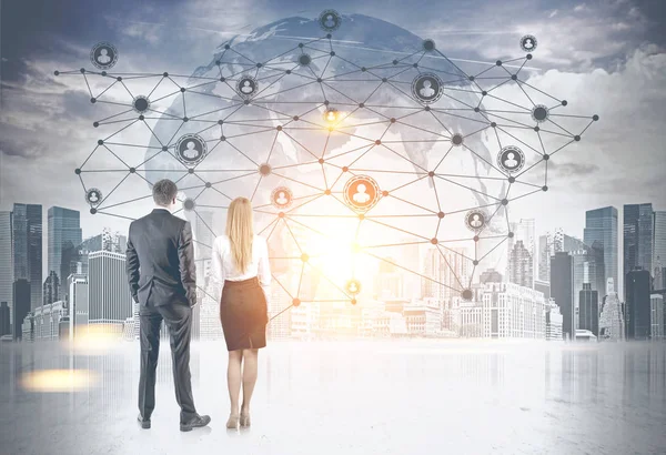 Young and successful business partners looking at a global network interface against an Earth hologram in modern city sky. Toned image double exposure mock up. Elements of this image furnished by NASA