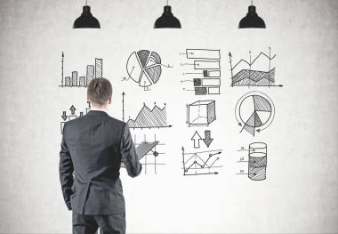 Dikiz gri elbiseli bir klasör tutan genç bir işadamı. O iple çekiyor. Grafikleri ve diyagramları beton duvara çizilen