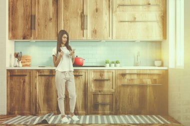 Mavi ve beyaz duvarlar, ahşap zemin, ahşap mutfak tezgahı ve dolapları ve sandalye, önden görünüm ile beyaz bir tablo ile beyaz İskandinav mutfak. Kadın 3d render kadar alay tonda görüntü çift pozlama