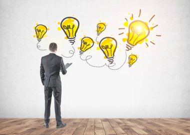 Dikiz gri elbiseli bir klasör tutan genç bir işadamı. O iple çekiyor. Sarı Işık Ampüller beton duvara. Bir fikir kavramı