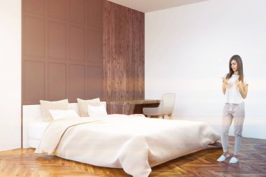 Beyaz ve gri duvar yatak köşe beyaz bir yatak, bir tablo ile bilgisayar ve bir ahşap zemin üzerinde bir akıllı telefon olan kadın. 3D render sahte kadar çift tonlu görüntü pozlaması