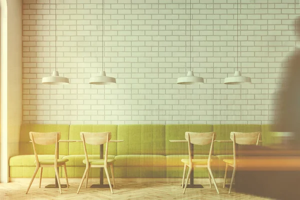 Industrial style cafe interior with white brick walls, a wooden floor, and wooden tables with chairs and green sofas. People. 3d rendering mock up toned image double exposure blurred