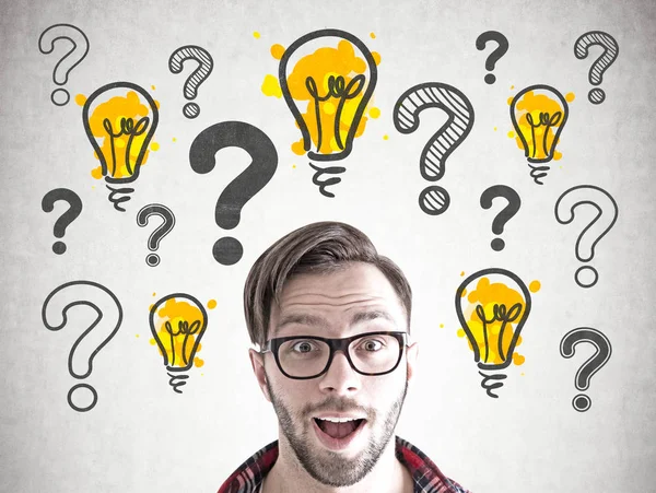 Pek çok soru işaretleri ve hafif bubls beton duvara yakın açık ağzı ile ayakta gözlüklü adam şaşırmış gibi yenilikçi.