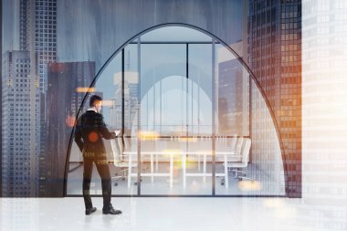 İşadamı koyu ahşap ofis lobisinde kemerli kapı ve bir uzun toplantı salonu ile beyaz bir zemin, Masa yanında ayakta beyaz sandalye ile. 3D render sahte kadar çift tonlu görüntü pozlaması