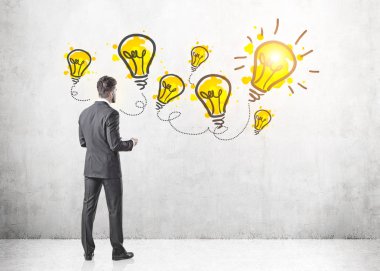 Gri takım elbise giymiş bir sakallı genç işadamı duran ve kağıtları tutarak. O iple çekiyor. Sarı Işık Ampüller bir duvar. Bir fikir kavramı