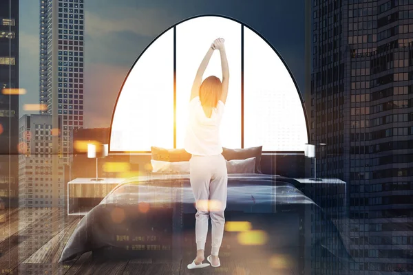 Bir yatak odası iç koyu gri duvarlar, bir ana yatak ve iki lamba başucu tabloları üzerinde duran bir kadın. Kemerli pencereler. 3D render sahte kadar çift tonlu görüntü pozlaması