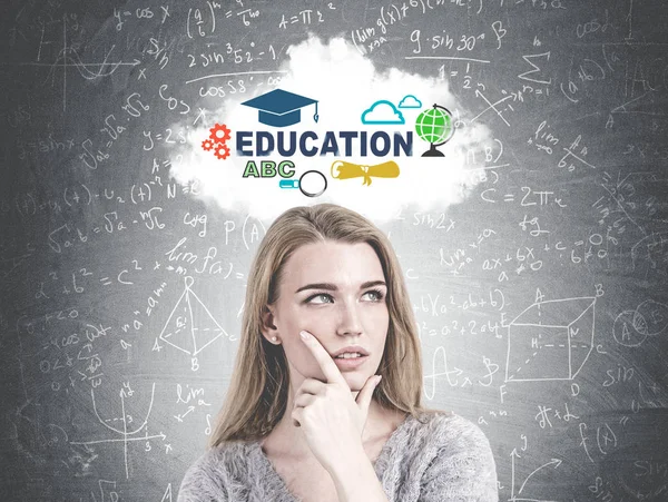 Head and shoulders portrait of a gorgeous young woman with gray eyes and blond hair looking into distance and thinking. A blackboard background with an education sketch and formula on it.