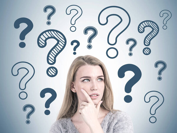 Голова и плечи портрет великолепной молодой женщины с седыми глазами и светлыми волосами, смотрящей вдаль и думающей. Многие вопросительные знаки на серой стене
.