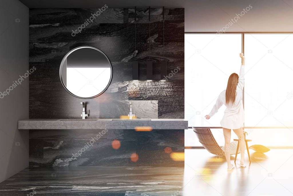 Black marble luxury bathroom interior with a deck chair and a sink with a round mirror. A loft window and a woman. 3d rendering mock up toned image