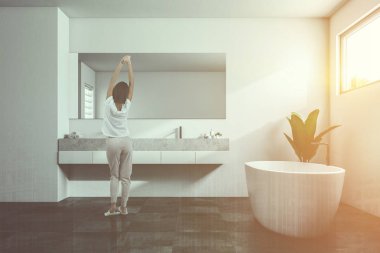 Beyaz duvarları, kiremitli bir siyah zemin, beyaz bir küvet, duş ve bir çift lavabo ile lüks banyo iç. Dar yatay pencere. Pijama 3d render kadında görüntü çift pozlama tonda