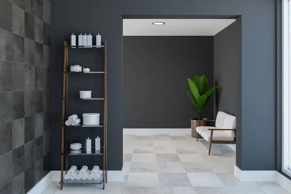 Shelves with towels and shampoo in a spacious bathroom interior with black tile and gray walls, a white wooden floor and a white sofa in the background. 3d rendering