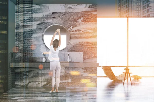Bir şezlong ve bir yuvarlak ayna ile lavabo ile gri mermer lüks banyo iç. Çatı penceresi ve bir kadın. 3D render sahte kadar çift tonlu görüntü pozlaması