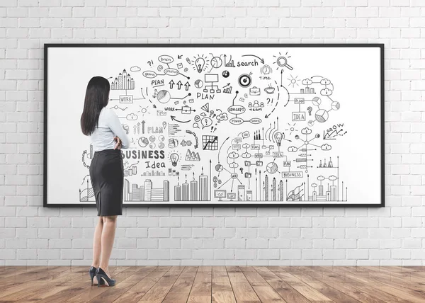 Tanınmayan bir genç beyaz işkadını yüksek topuklu bir beyaz tahta bir iş planı üzerine onun önünde bakarak bir etek ve gömlek giyen tam uzunlukta portresi.