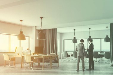 Bilgisayar masaları ve onlara yakın ahşap sandalye satır içeren bir açık alan office köşesindeki konuşurken iki iş adamları. Bilgisayar ekranları siyah. 3D render sahte kadar çift tonlu görüntü pozlaması