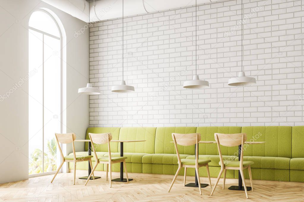 Corner of an industrial style cafe interior with white brick walls, a wooden floor, and wooden tables with chairs and green sofas. 3d rendering mock up
