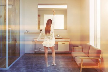 Kadın bir rahat banyo iç beyaz duvarlı, cam kapı, bir lavabo ve gri bir kanepe ile ahşap duş. 3D render tonlu görüntü