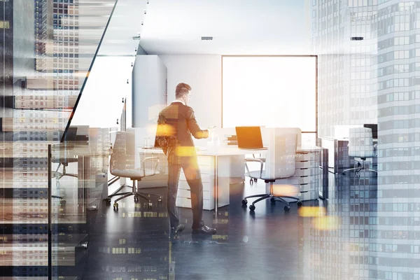 Businessman in a white walls office interior with a concrete floor, loft windows, a staircase and white computer tables. 3d rendering mock up toned image double exposure