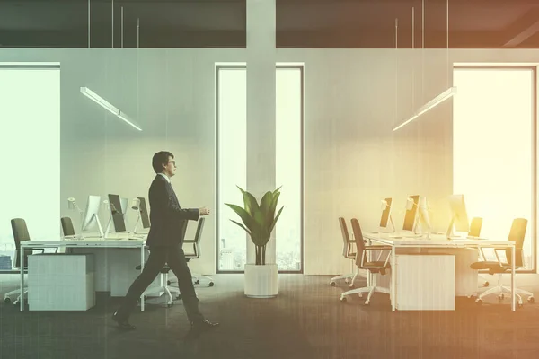 Businessman walking in a modern international corporation office with white walls, and white computer desks. Industrial style. Black ceiling. 3d rendering mock up toned image double exposure