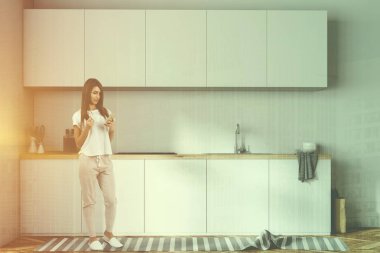 Kadının yanına beyaz mutfak tezgahları bir Ocak, mutfak eşyaları ve onları şişe. Bir dizi üzerinde beyaz odasında asılı dolaplar. 3D render sahte kadar çift tonlu görüntü pozlaması