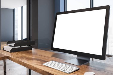 Boş bilgisayar ekran bir mavi duvar çatı odasında yer alan bir ofis iç ahşap bir masa üzerinde duran. Yan görünümü. 3D render alay