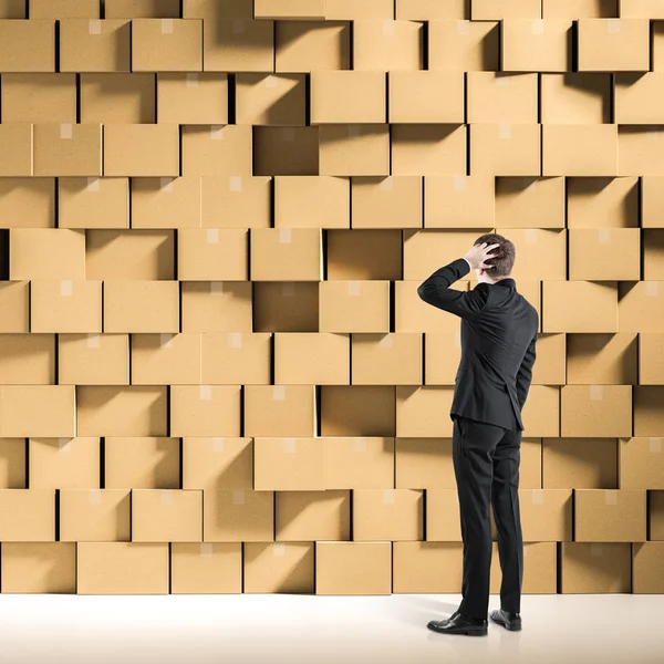 Confused Businessman Scratching Head Looking Wall Closed Cardboard Boxes Stacked — Stock Photo, Image