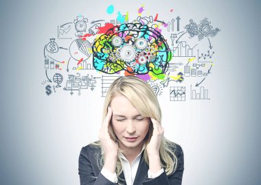 Şiddetli bir baş ağrısı olan bir takım elbise giymiş uzun sarı saçlı Genç beyaz işkadını. Renkli cog beyin kroki ve bir iş planı üzerine bir gri duvar arka plan.