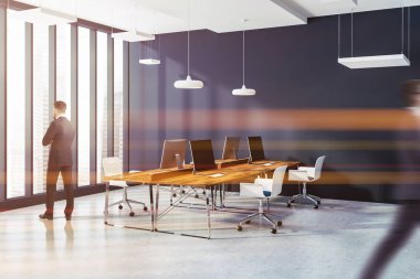 Açık alan ofis iç koyu mavi duvarlar, beton zemin, ahşap Bilgisayar masaları ve beyaz sandalye ile. Bir cityscape çatı pencere. İş adamları. 3D render sahte tonlu görüntü bulanık