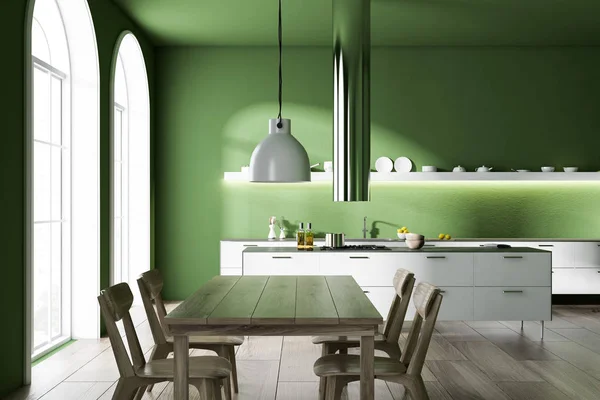 Modern kitchen interior with green walls, a wooden floor, arched windows and white countertops. A long table with chairs. 3d rendering mock up