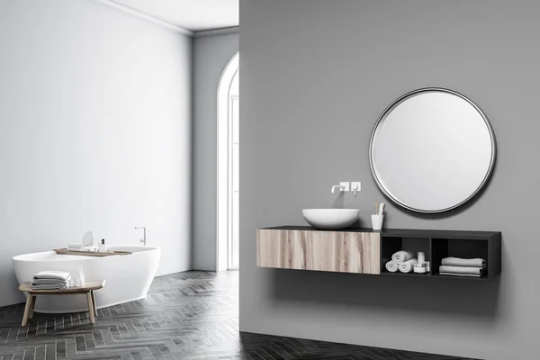 Corner of a large bathroom interior with grey walls, a wooden floor, a sink with round mirror and a bathtub. Arched window. 3d rendering mock up — Stock Image Corner Large Bathroom Interior Grey Walls Wooden Floor Sink Mirror Royalty Free Stock Images