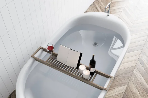 Elegant white bathtub filled with water standing in a luxury bathroom interior with white tiled walls, and a wooden floor. A mock up open book on a shelf. 3d rendering top view — Stock Image Elegant White Bathtub Filled Water Standing Luxury Bathroom Interior White Stock Photo