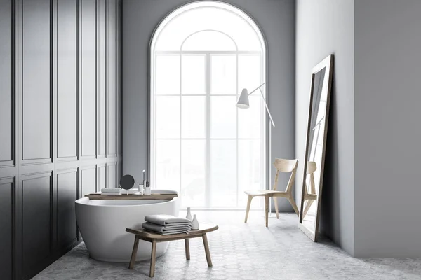 Elegant white bathtub filled with water standing in a luxury bathroom with gray walls, and a hexagon tile floor. A mirror on the shelf. 3d rendering — Stock Image Elegant White Bathtub Filled Water Standing Luxury Bathroom Gray Walls Royalty Free Stock Images