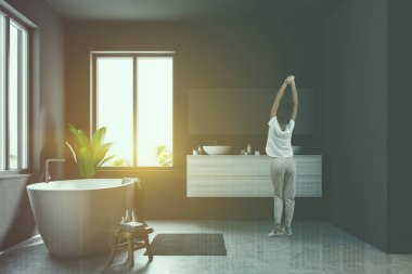 İskandinav banyo iç Gri duvarlar, beton zemin, geniş pencereler ve bir çift lavabo yanında beyaz küvet durduğunu kadında. Şehir 3d render kadar alay tonda görüntü çift pozlama