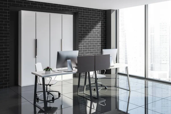Minimalistic office interior with black brick walls, a black tile floor, computer desks and a window with a city view. 3d rendering mock up