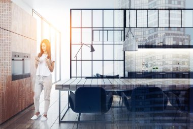 Kadın siyah ve beton duvar mutfak ve yemek odası iç ahşap zemin, kahverengi dolaplar, siyah mutfak tezgahı ve ahşap bir masa sandalye ile. 3D render resim çift pozlama tonda