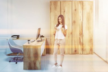 Beyaz duvarları, uzun ahşap dolap ve beyaz bir sandalye ile bir bilgisayar tablo Yöneticisi ofiste bir akıllı telefon olan kadın. 3D render sahte tonlu görüntü