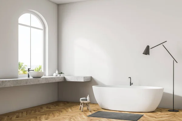 White wall bathroom corner with wooden floor, arched windows, white bathtub, and double sink. Floor lamp. 3d rendering mock up
