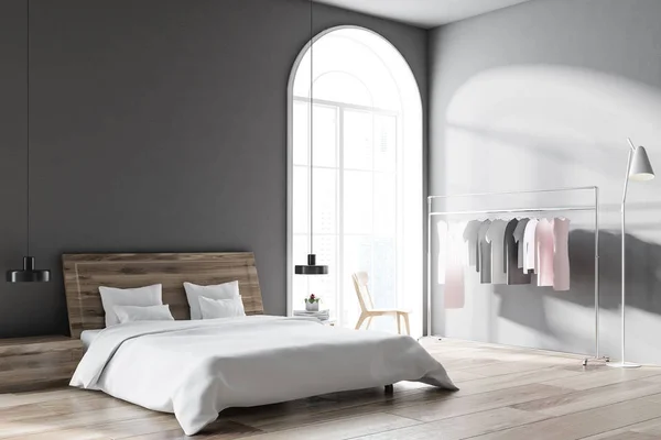 Scandinavian style bedroom with grey walls, a wooden floor, a clothes rack, and a master bed with bedside tables. Arched windows. 3d rendering mock up